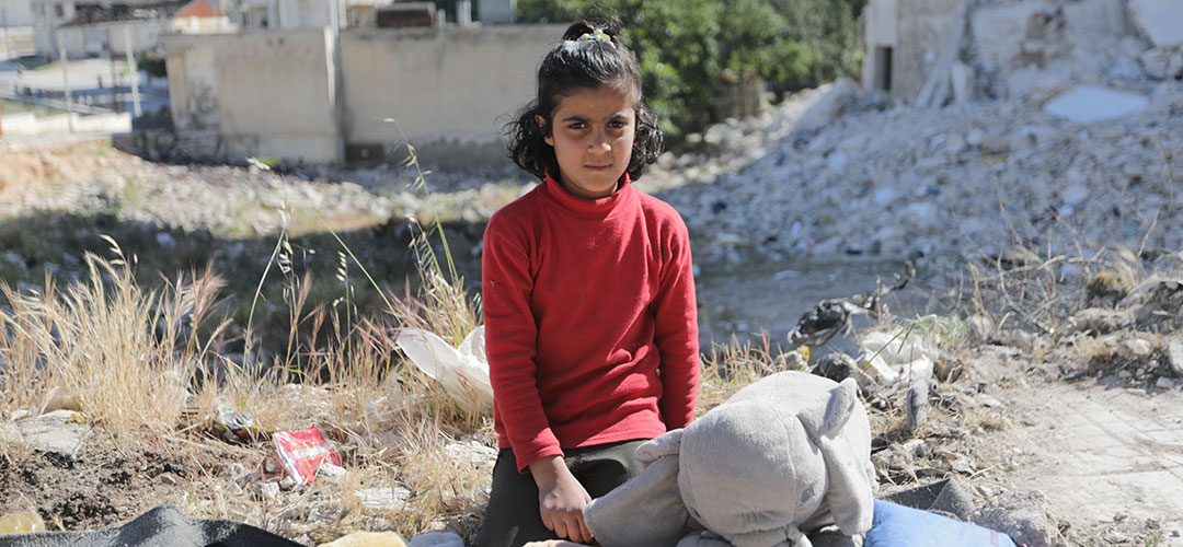 Dara* (10) verkauft in den Ruinen von Idlib Spielsachen, um zum Familieneinkommen beizutragen. Das syrische Mädchen musste mit seinen Eltern und zwei Geschwistern fliehen, als ihr Dorf in der Region Idlib zunehmend unter Beschuss geriet. Ein Rettungswagen nahm sie mit in ein anderes Dorf, später zog die Familie in ein zerstörtes, leerstehendes Wohnhaus in der Stadt Idlib. Der Vater, der durch die Angriffe am Kopf, Arm und Bein verletzt wurde, fand keine Arbeit und verdingt sich als Müllsammler. © Save the Children