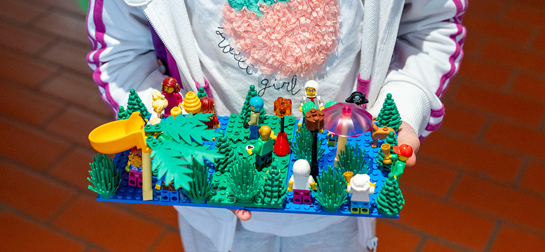 Mit LEGO Steinen Zukunft entwerfen. © Mauro Bedoni / Save the Children Ein Kind hält eine LEGO Konstruktion hoch.