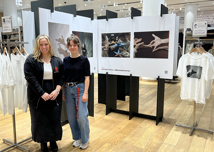 MAGNUM-Fotoausstellung im UNIQLO-Store in Berlin-Tauentzien. © Save the Children Zwei Mitarbeitende von Save the Children vor Plakaten einer Fotoausstellung im UNIQLO-Store.