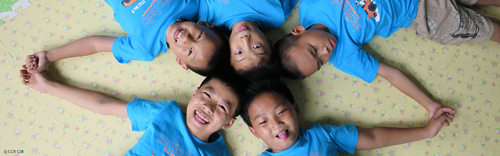 Fünf Jungs in blauen T-Shirts, die mit ihren Köpfen im Kreis liegen Fünf Jungs in blauen T-Shirts, die mit ihren Köpfen im Kreis liegen