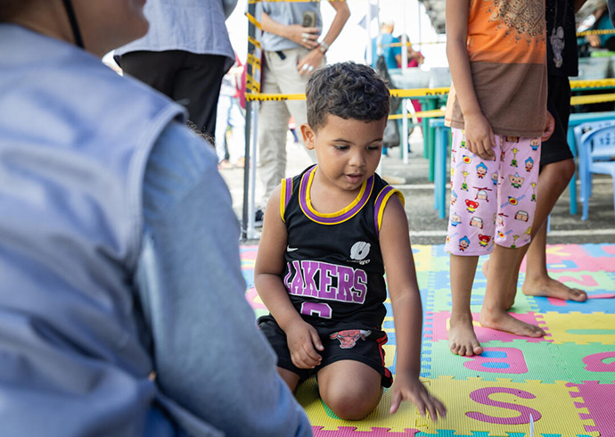In Notsituationen wie nach den Erdbeben in Venezuela errichten wir Schutz- und Spielräume. © Miguel Vera / Save the Children Ein Kind sitzt auf einem bunten ABC-Teppich