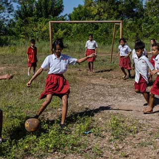 Gegen die Klimakrise: Kinder in Indonesien können wieder lernen und spielen, da Save the Children ihre Familien mit Lebensmitteln, Bargeld und einer Wasserpumpe unterstützt. © Ulet Ifansasti / Save the Children Kinder in Schuluniformen spielen Fußball.