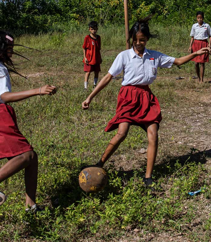 Kinder in Schuluniformen spielen Fußball.