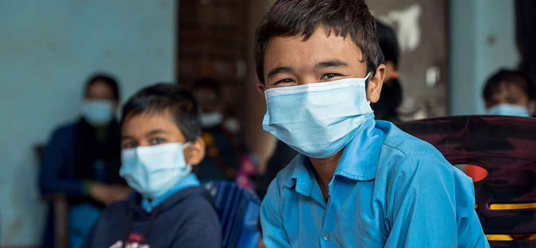 Zwei Schuljungen mit Atemschutzmaske blicken frontal in die Kamera. © Save the Children/Robic Upadhayay