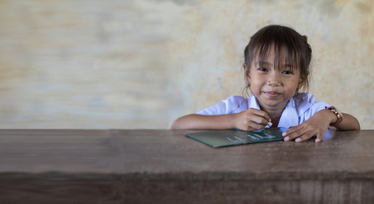 Ein Mädchen schreibt auf eine Schiefertafel © Save the Children