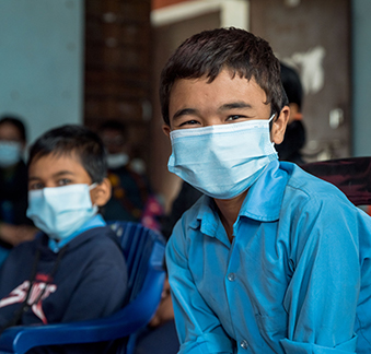 Zwei Schuljungen mit Atemschutzmaske blicken frontal in die Kamera. © Save the Children/Robic Upadhayay