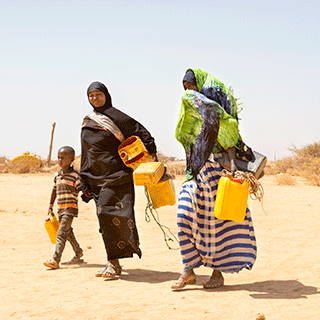 Zwei Frauen in Somaliland tragen leere Wasserkanister durch die Wüste